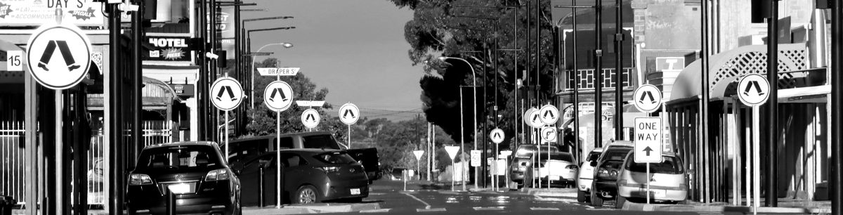 Suburban shopping street with parked cars and shopfronts